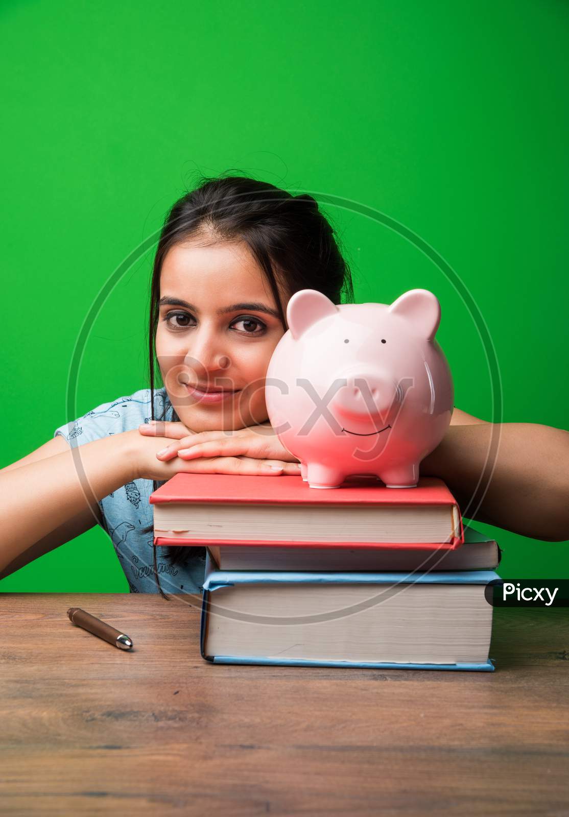 Indian/asian attractive female student with holding piggy bank and books