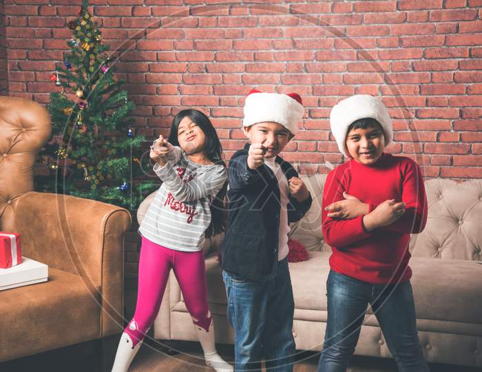Cute little Indian/Asian kids celebrating christmas at home with Santa Hat, Gifts and Xmas Tree