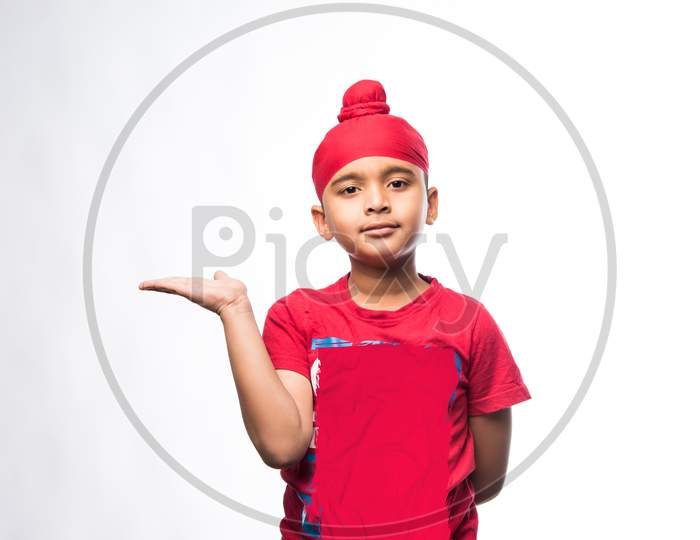 Portrait of Indian Sikh/punjabi little boy presenting while standing isolated over white background