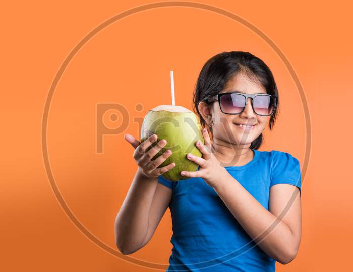 Cute little Indian girl drinking coconut water / nariyal pani