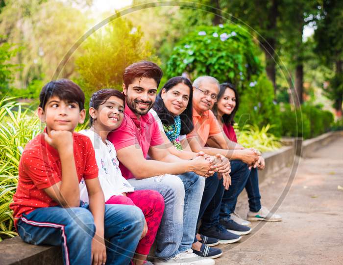 indian family of 6 sitting at wall in garden / park