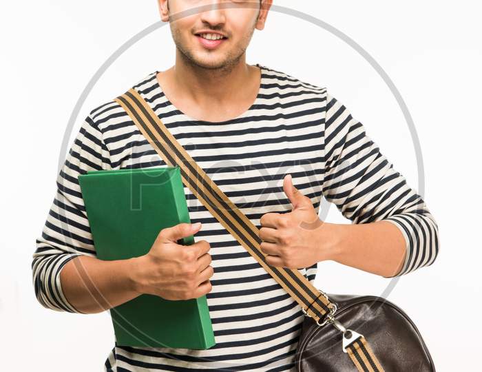 Young male college student standing with bag and books/laptop computer, isolated over white background