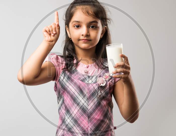 Cute little girl drinking Milk from glass