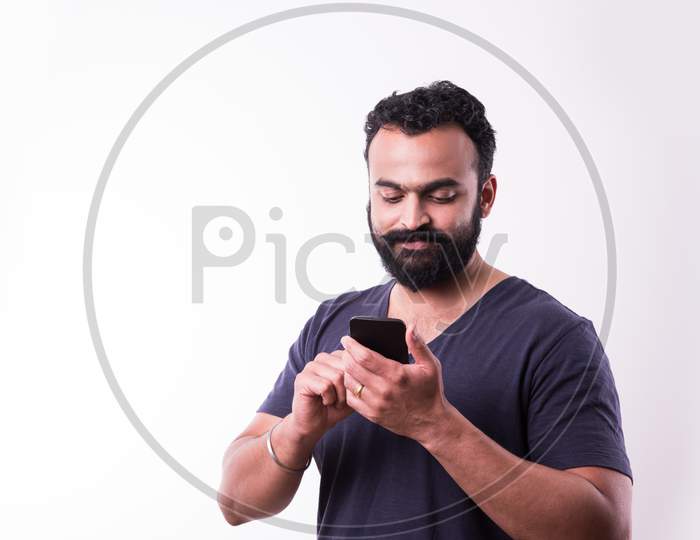 Indian Bearded young man calling or using smartphone