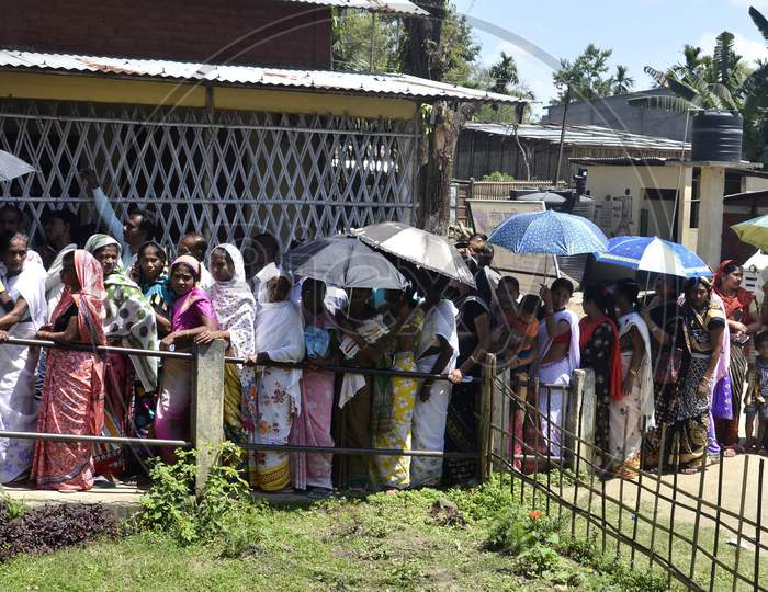 Women voters holding umbrellas to protect themselves from heat as they queue to cast their vote