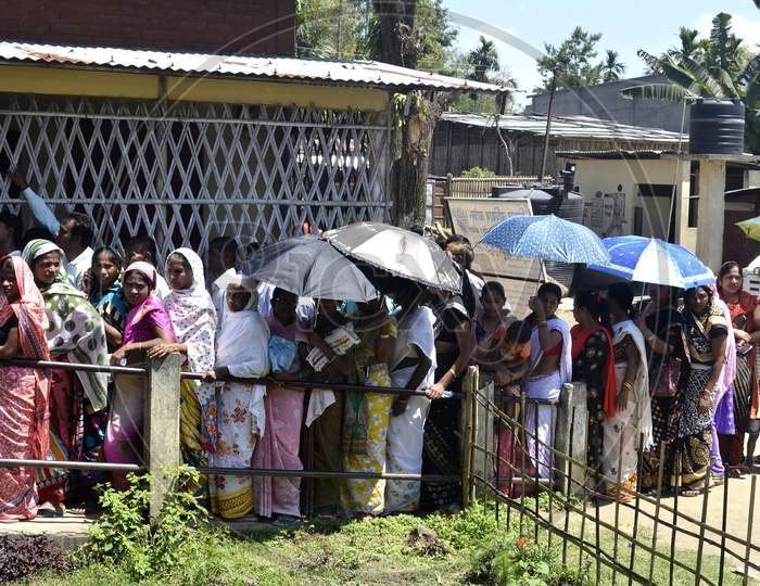 Women voters holding umbrellas to protect themselves from heat as they queue to cast their vote