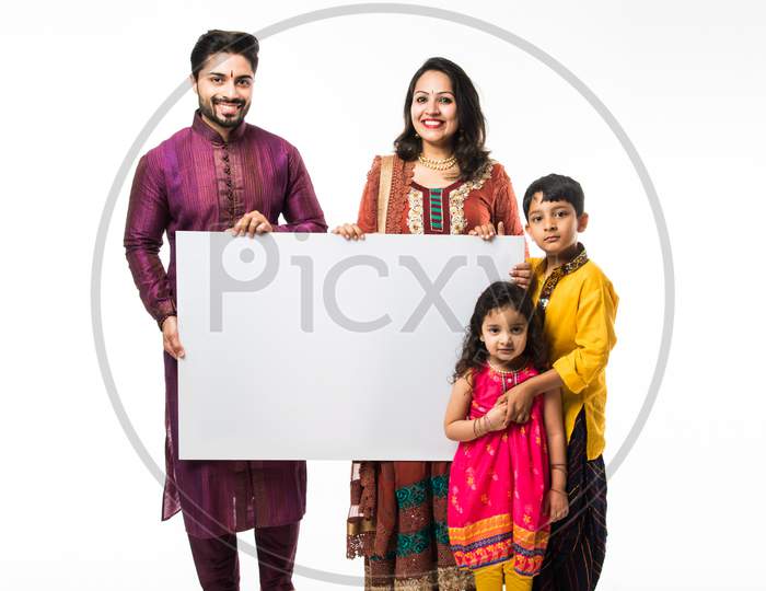 Indian family celebrating Diwali while holding blank white board / placard. Standing isolated over white background and looking