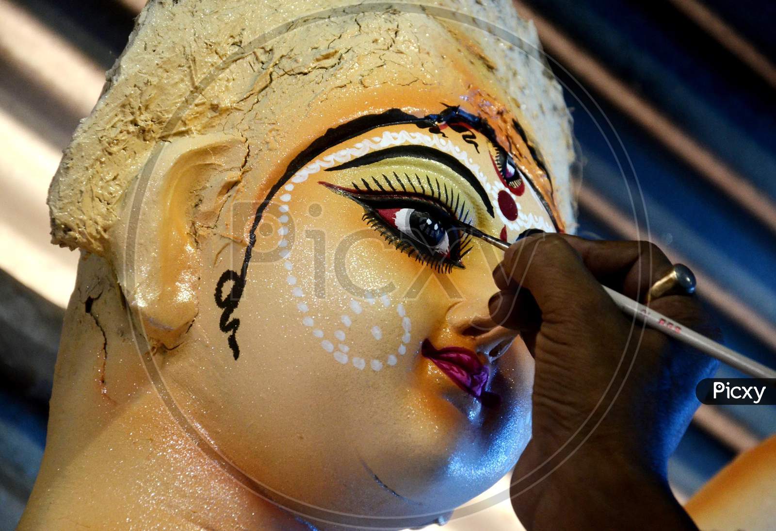 An artist gives final touches to an idol of Goddess Durga