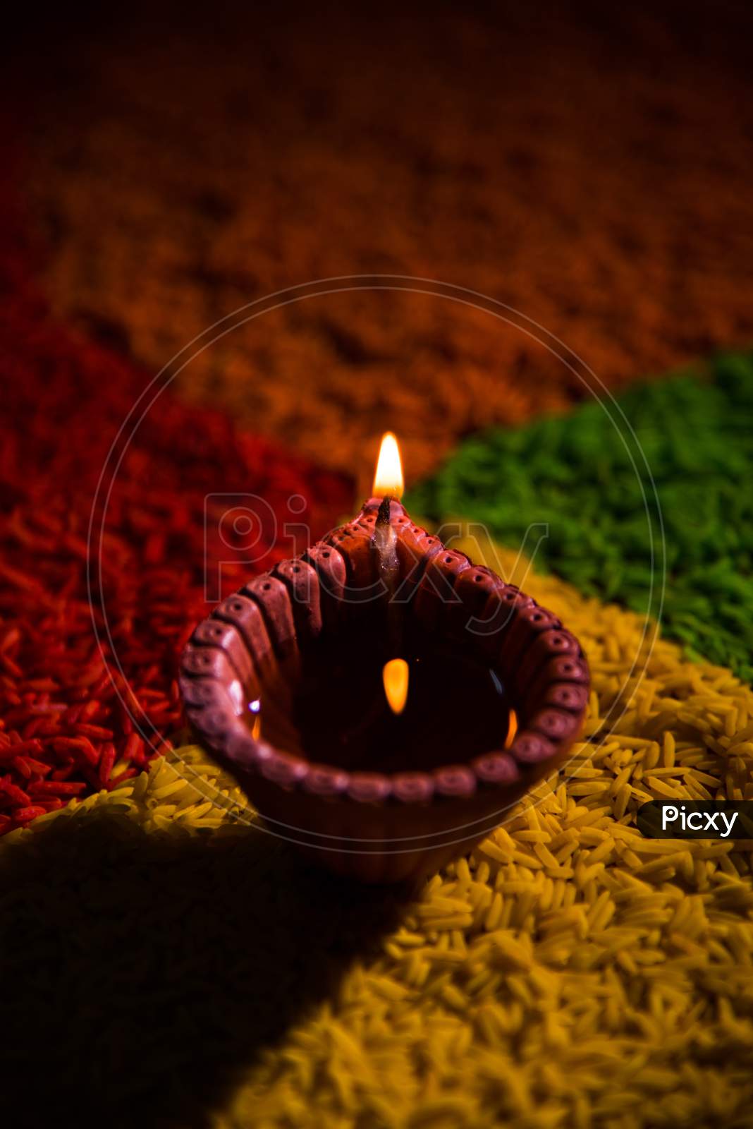 Diwali Diya over Rangoli made using Colourful Rice grains
