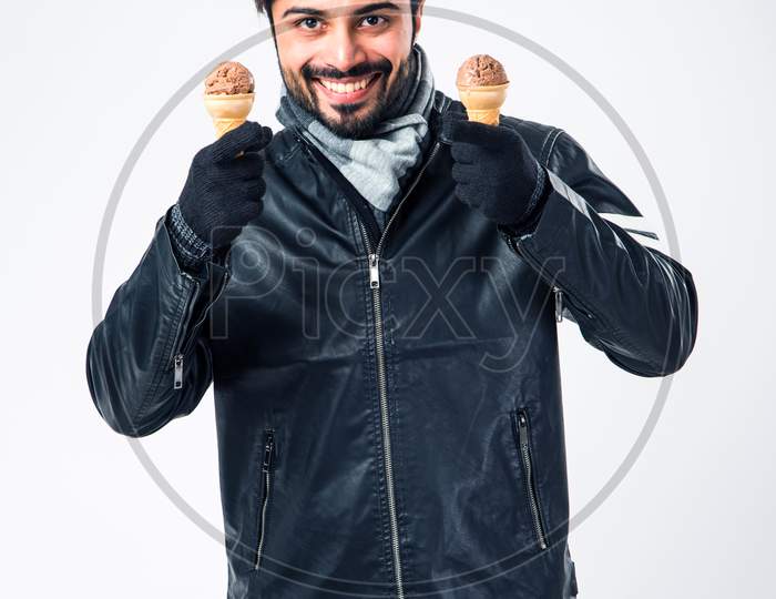 Indian man eating Ice Cream in warm clothes on white background