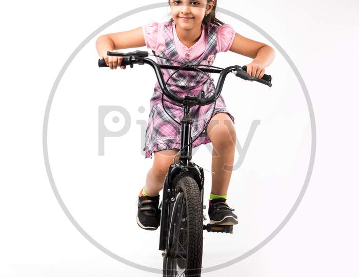 Cute little Indian/asian girl riding on bicycle, isolated over white background