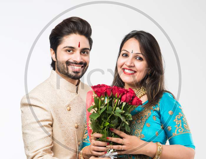 Indian Man giving rose flowers bouquet to wife, standing isolated over white background