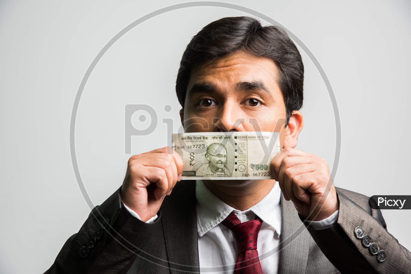 Indian young businessman bribing concept with paper currency covering mouth