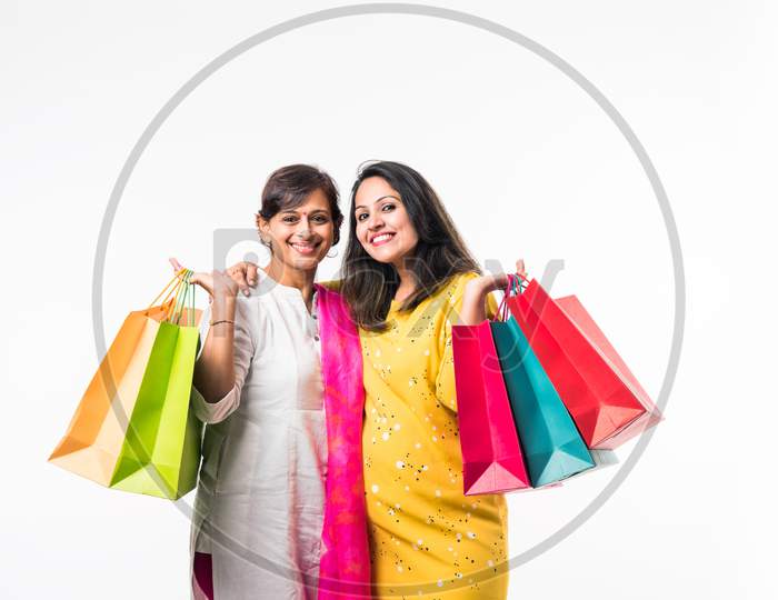 Indian Mother daughter sisters shopping with colourful bags, standing isolated over white background