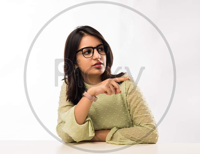 Indian girl sitting at table with resting chin on hands
