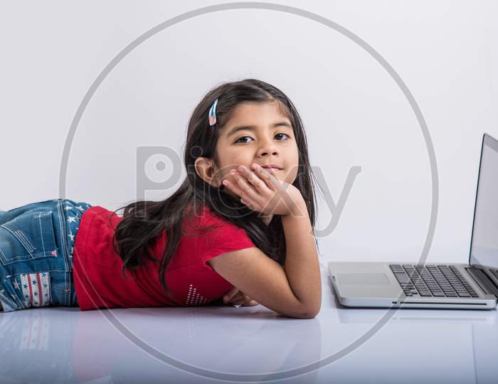 Indian school girl studying with laptop on floor