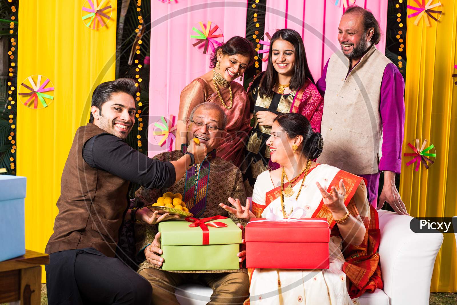 multigenerational Indian Family eating sweets while celebrating diwali festival or occasion