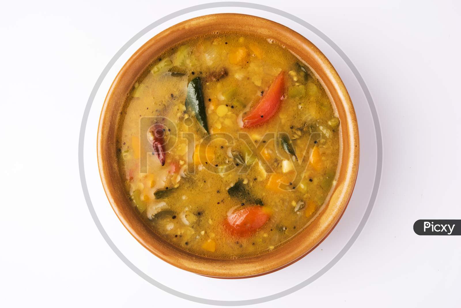 south indian vegetable sambar, in earthen bowl on white background