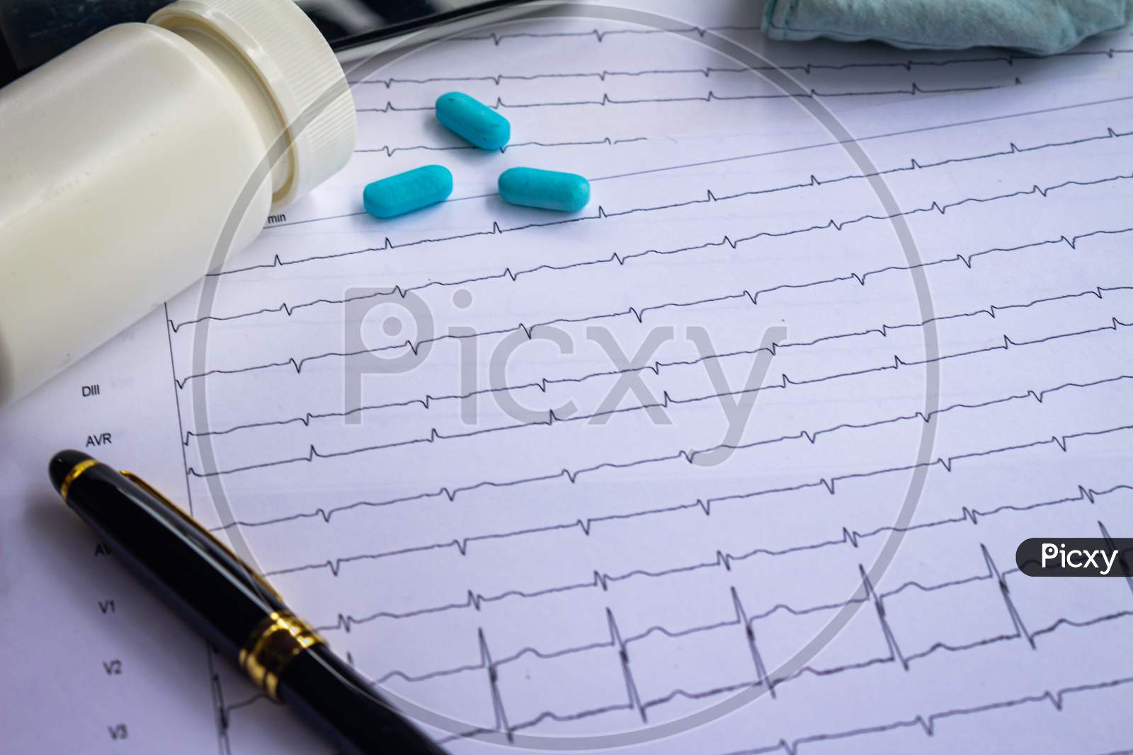 Top View Of A Desk With Various Elements Of Medicine. Pills On Electrocardiogram