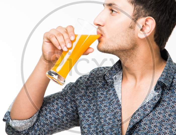Young man having cold drink or fresh juice in a glass