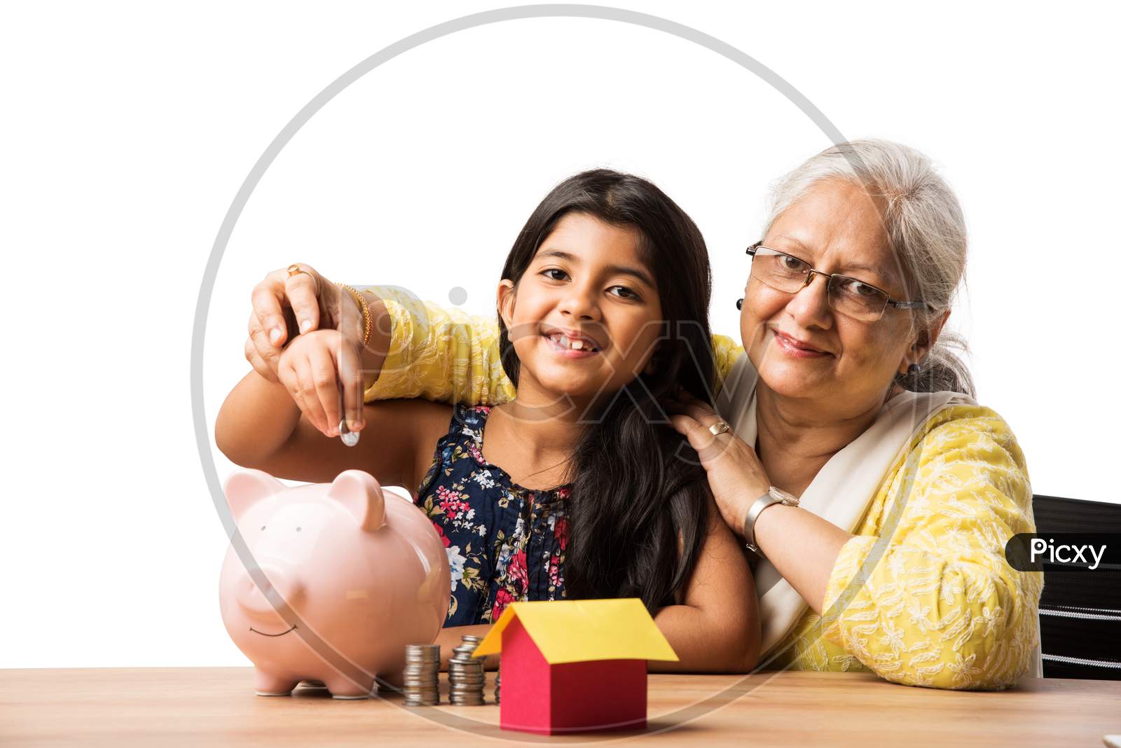 Small Girl inserting Rupee in piggybank with grand mother