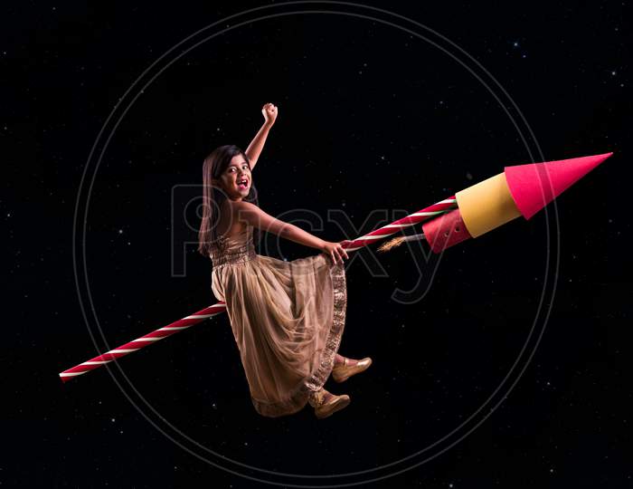 Concept showing cute indian girl riding on Diwali Rocket and travelling to space