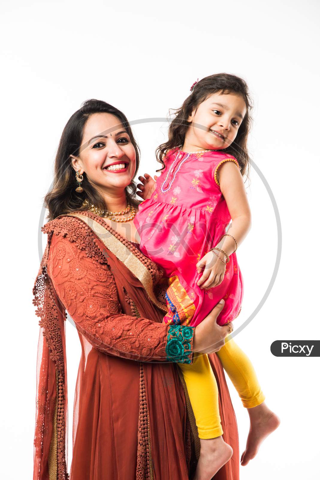 Portrait of Happy Indian mother hugging her daughter in traditional ethnic clothes on some festival day, standing isolated over
