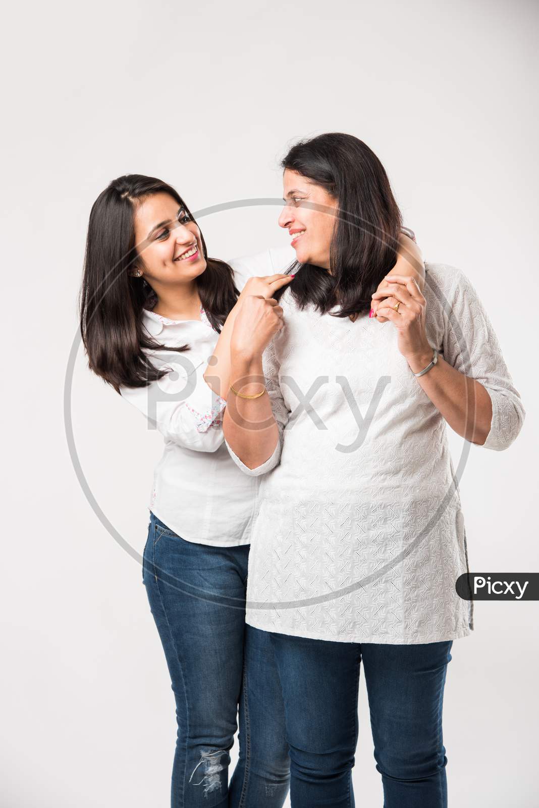 Old mother with young daughter, standing isolated over white background
