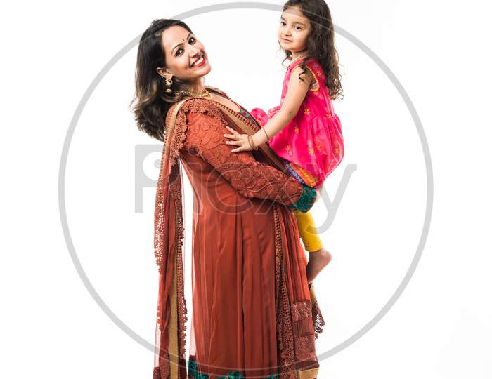 Portrait of Happy Indian mother hugging her daughter in traditional ethnic clothes on some festival day, standing isolated over
