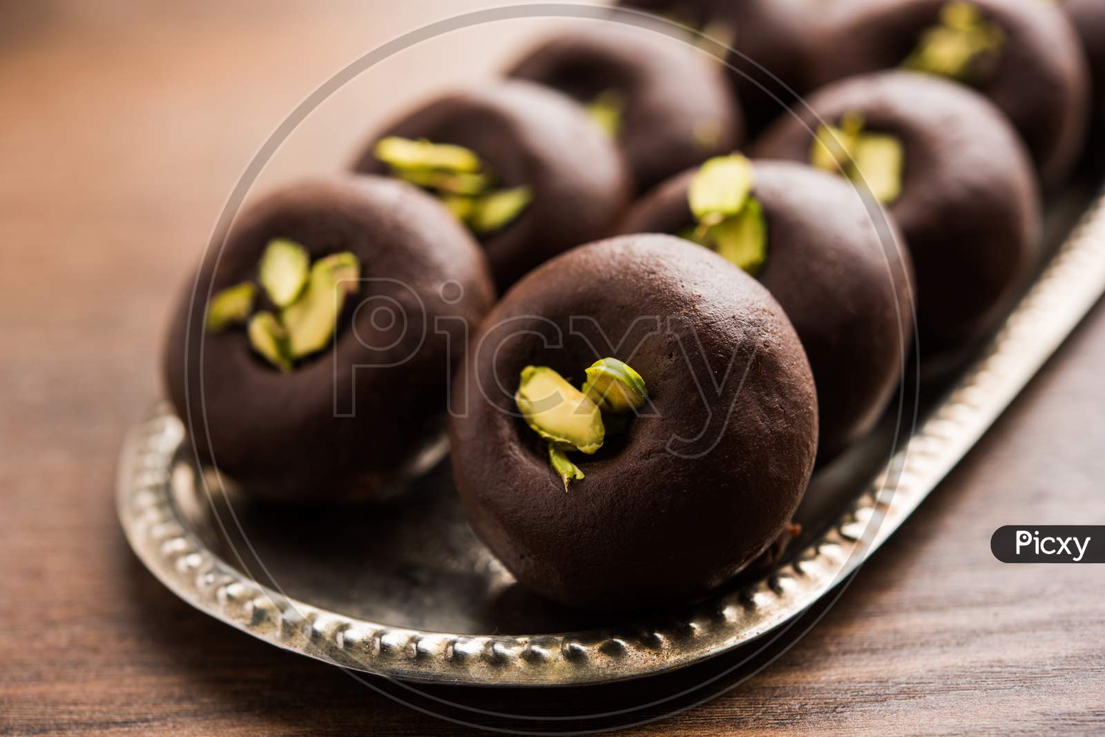 Chocolate Milk peda or pera or pedha made using sweet condensed Milk and cocoa powder, garnished with Pistachio. selective focus