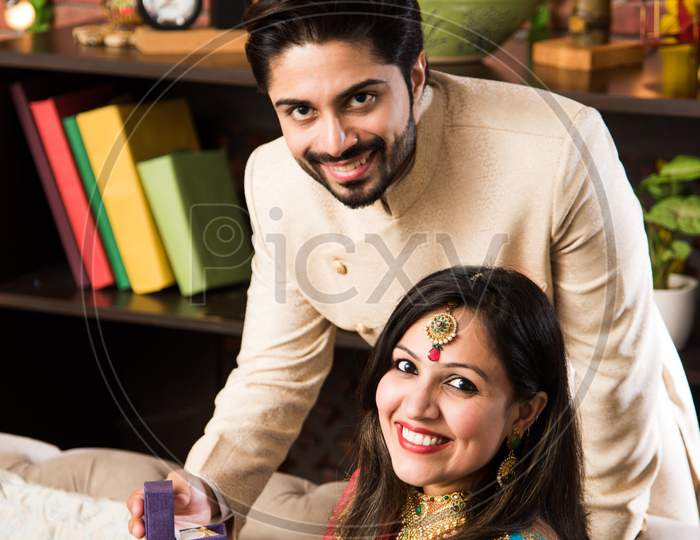 Indian man giving surprise gift to wife, jewellery on Diwali or Wedding anniversary, selective focus