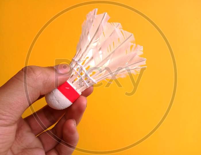 Holding A Shuttlecock In A Hand Yellow Background
