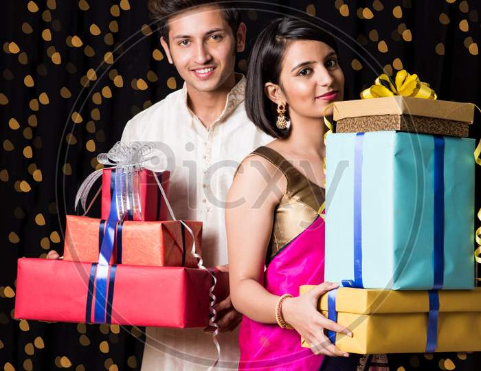 Indian young couple holding gift boxes