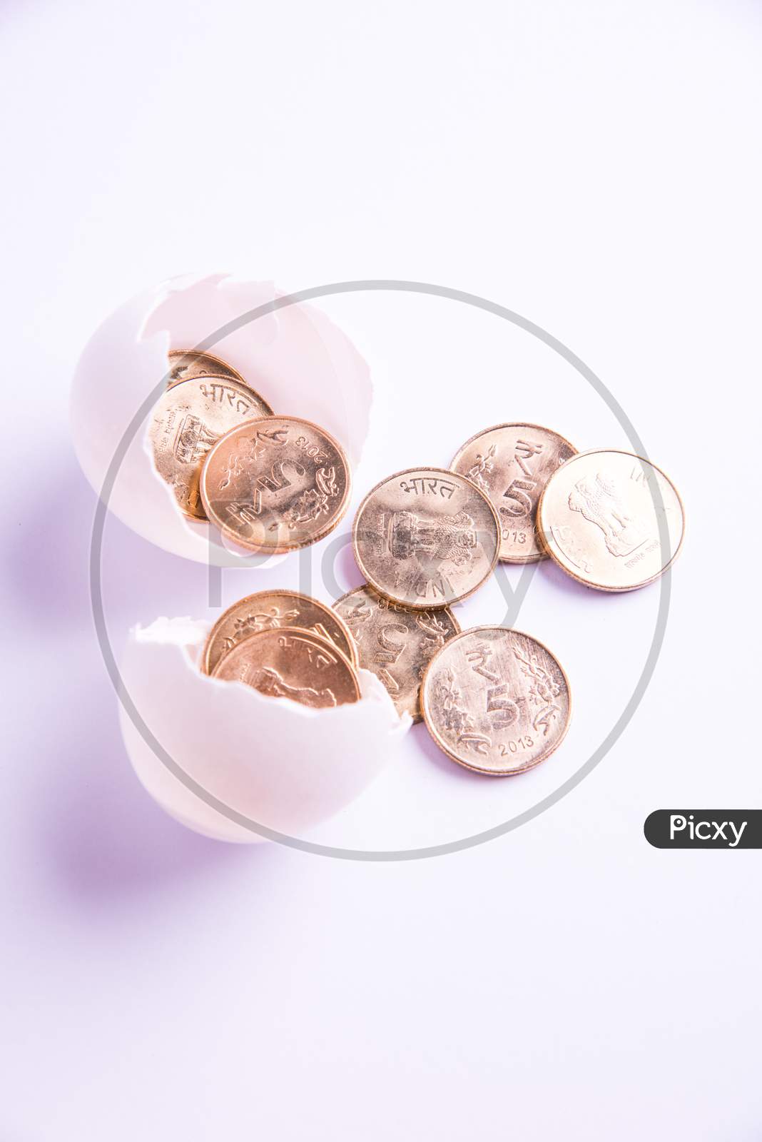 indian five rupee golden coins emerging from cracked egg, isolated over white background