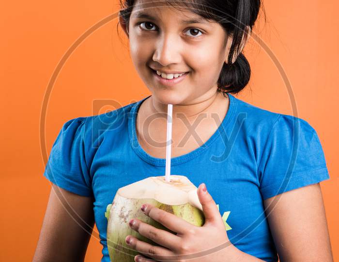 Cute little Indian girl drinking coconut water / nariyal pani