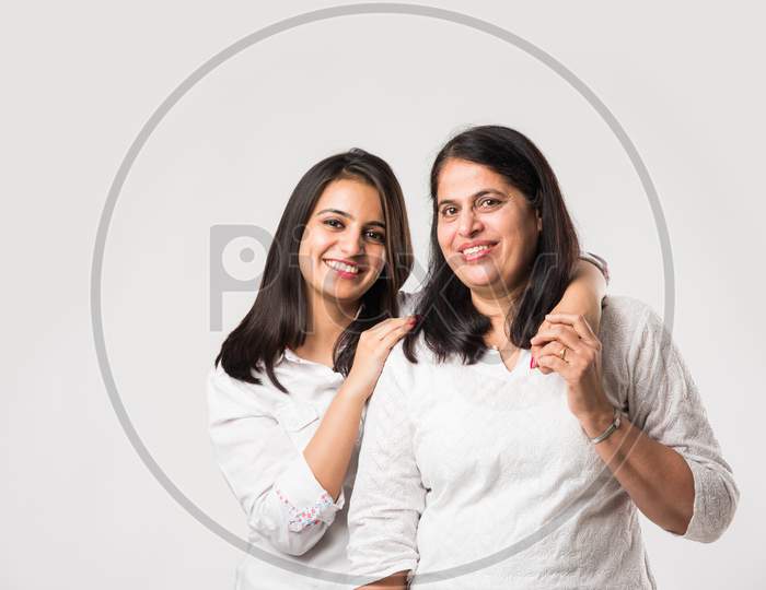 Old mother with young daughter, standing isolated over white background