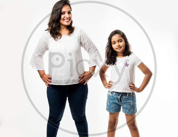 Indian small girl and mother standing over white background measuring height difference