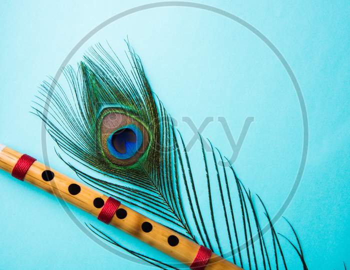 peacock feather and bamboo flute over colourful background