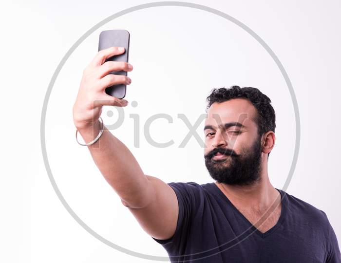 Indian Bearded young man calling or using smartphone