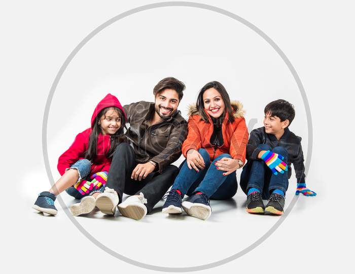Indian family in warm clothes sitting against white background. Ready for winter