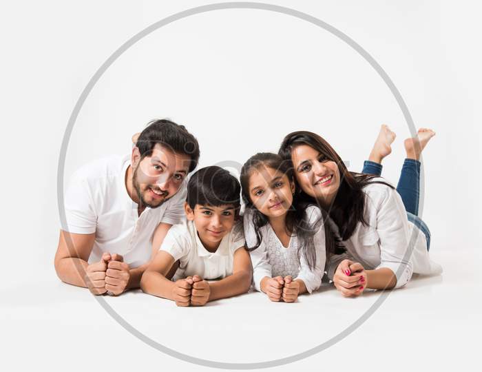 Young family lying on white looking at camera