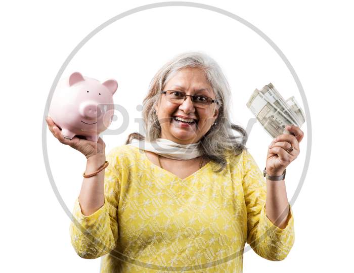 Senior woman holding money fan and piggy bank