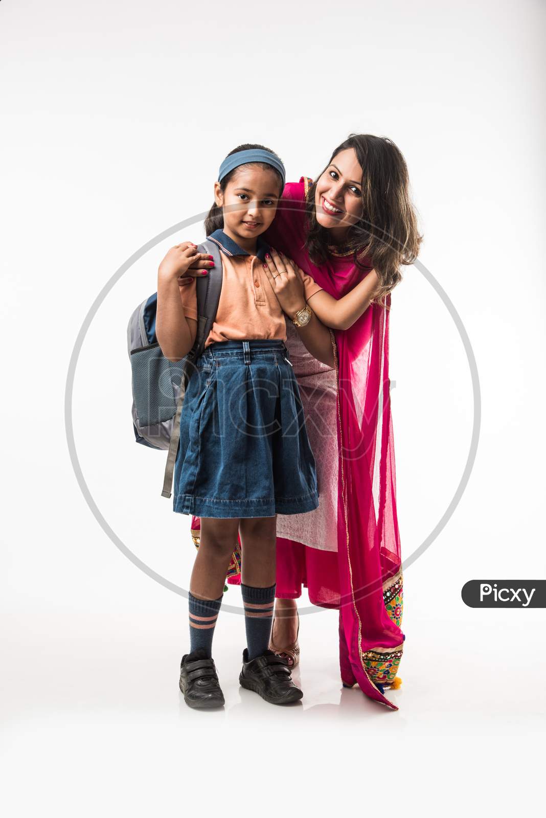 Indian Mother helping school girl with uniform getting ready with Lunch Box, hair style or waiting for school bus