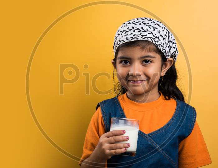 Small girl drinking plain milk in a glass before going to school