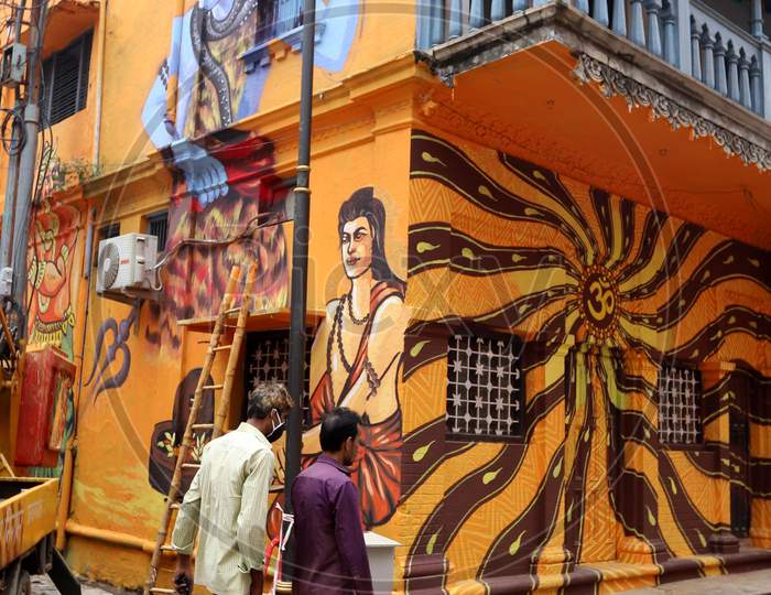 People walk in front of a mural during the lockdown in Prayagraj, Uttar Pradesh on July 11, 2020