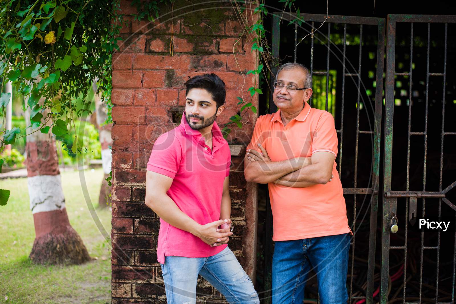 Young Man with Father posing against red brick wall, outdoor