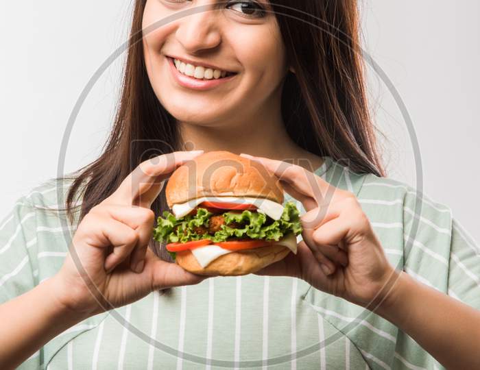 Beautiful young girl eating burger