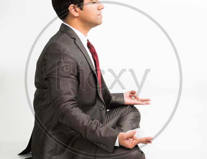 Indian young businessman doing yoga / pranayama / exercise
