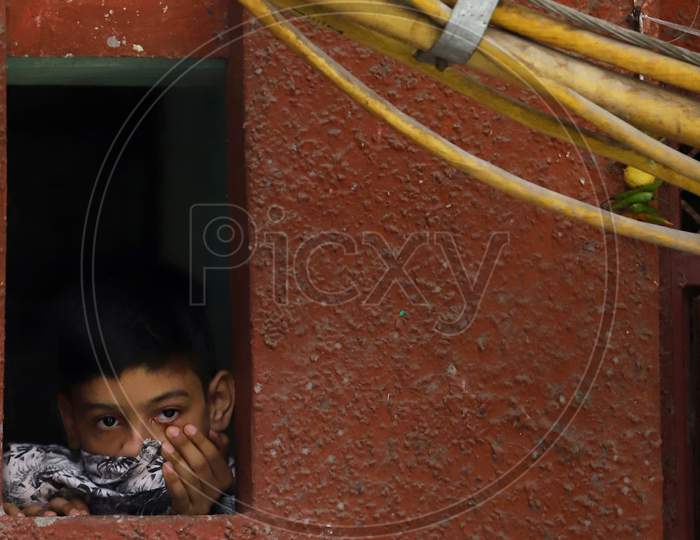 A boy peeps through a window of his house in a containment zone in New Delhi on July 06, 2020