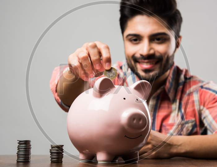 Indian Man with Piggy Bank, sitting at table